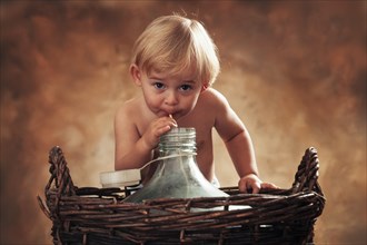 Three year-old girl drinking through a straw from glass carboy