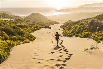 Woman running down dunes