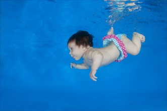 4 months infant learning to swim underwater in a pool