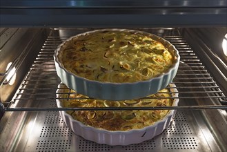 Two baked leek quiches in round form in the oven