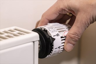 Hand adjusts the temperature at a thermostat of the heating