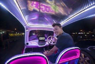 Young man driving a colorful car illuminated with LEDs
