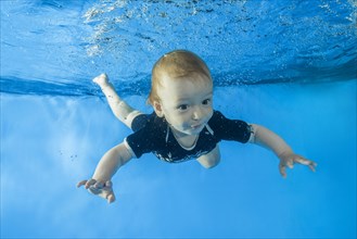 Little boy dives underwater in swimming pool