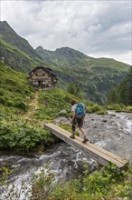 Hiker crosses wooden bridge across mountain stream