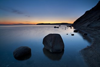 Coastline with big boulders on beach at sunset