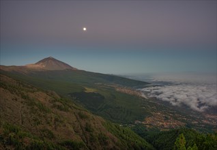 Night view of trade wind clouds over Orotava valley with Pico del Teide in front of sunrise