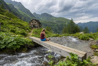 Hiker on wooden bridge across mountain stream