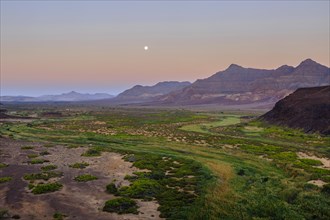 Moon rising in dry river valley