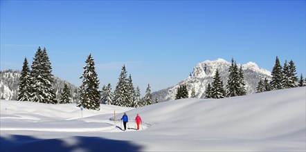 Two hikers walk through snow-covered mountain scenery