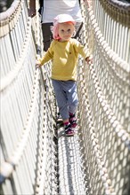 Toddler on a suspension bridge at a playground