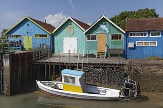 Colorful huts of oyster farmers and boat on a canal, Ile d'Oléron