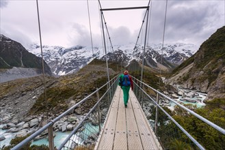 Hiker proceeds suspension bridge over River Hooker