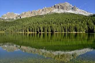 Mountain range Cadini di Misurina and dense mountain forest are reflected in Lake Misurina