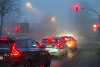 Cars at a red light in fog at night