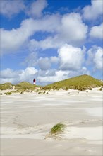 Dunes with lighthouse and cloudy sky