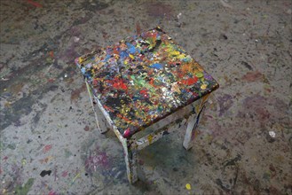 Footstool with colorful paint residues in a studio