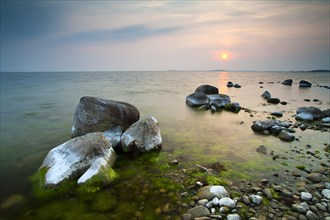 Coastline with big boulders on beach at sunset