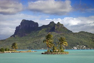 Small palm island in the sea in front of Mont Otemanu