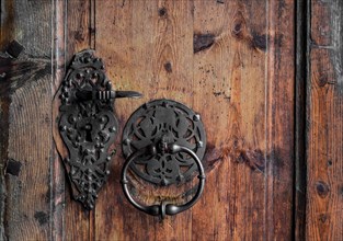 Forged door handle and knocker on an old wooden door