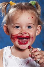 Four year old girl putting on lipstick