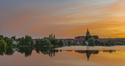 Cityscape with St. Nicholas' Church and lake Schulsee at sunset