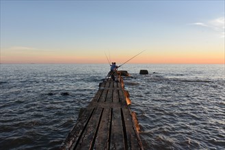 Old jetty with anglers at sunset
