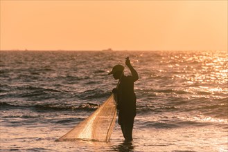 Local fishermen with fishing net in backlight