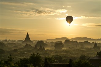 Hot air balloon at sunrise over temples and pagodas