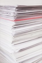 Pile of stacked white paper reports with red one sticking out