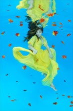 Young woman in yellow dress posing under water