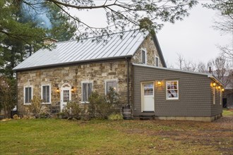 Old 1820 cottage style cut stone and fieldstone house facade with cedar shingles extension in autumn