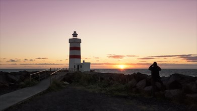 Man photographs sunset at lighthouse in Garour