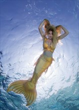 Golden-haired mermaid swims under the water