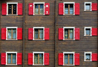 Windows with red shutters on wooden house