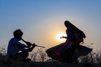 Indian gypsy dancing in front of setting sun