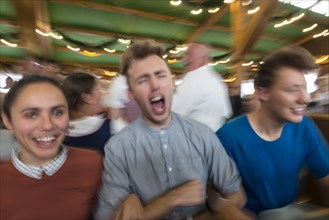 Three young people celebrate happily in a beer tent