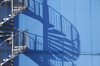 Spiral staircase and shadow on blue factory facade