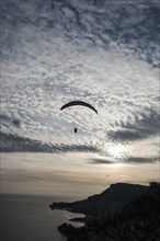 Paraglider against cloudy sky