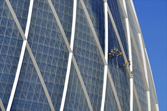 Window cleaners hang on the "The Coin" building