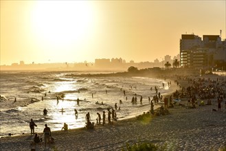 Many people bathing on the beach at sunset