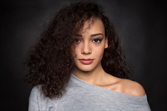 Young woman with curly hair in gray sweater