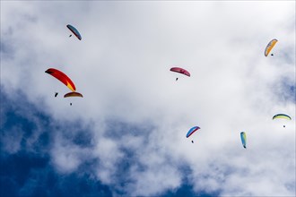 Many paragliders are flying in the air