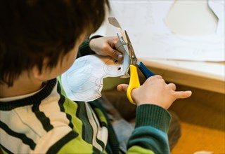 Child cuts pattern from paper with scissors