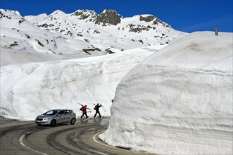 Car and two skiers in front of high snow walls