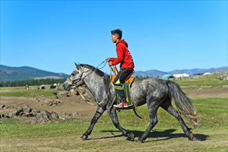Boy rides on a horse through the steppe