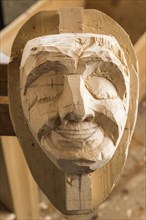 Carved face of an unfinished wooden mask