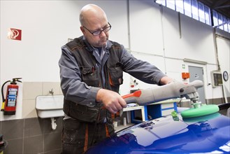 Coachbuilder master with the polishing machine on the car