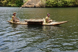Korafe girls paddling in a dugout canoe with outrigger