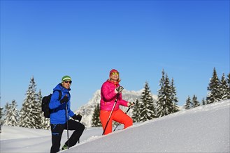 Two hikers walk through deep snow