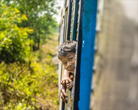 Small local boy looking out of moving train